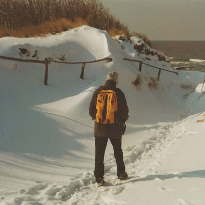 mein Herr Schatz mit gelbem wanderrucksack an der verschneiten Ostsee